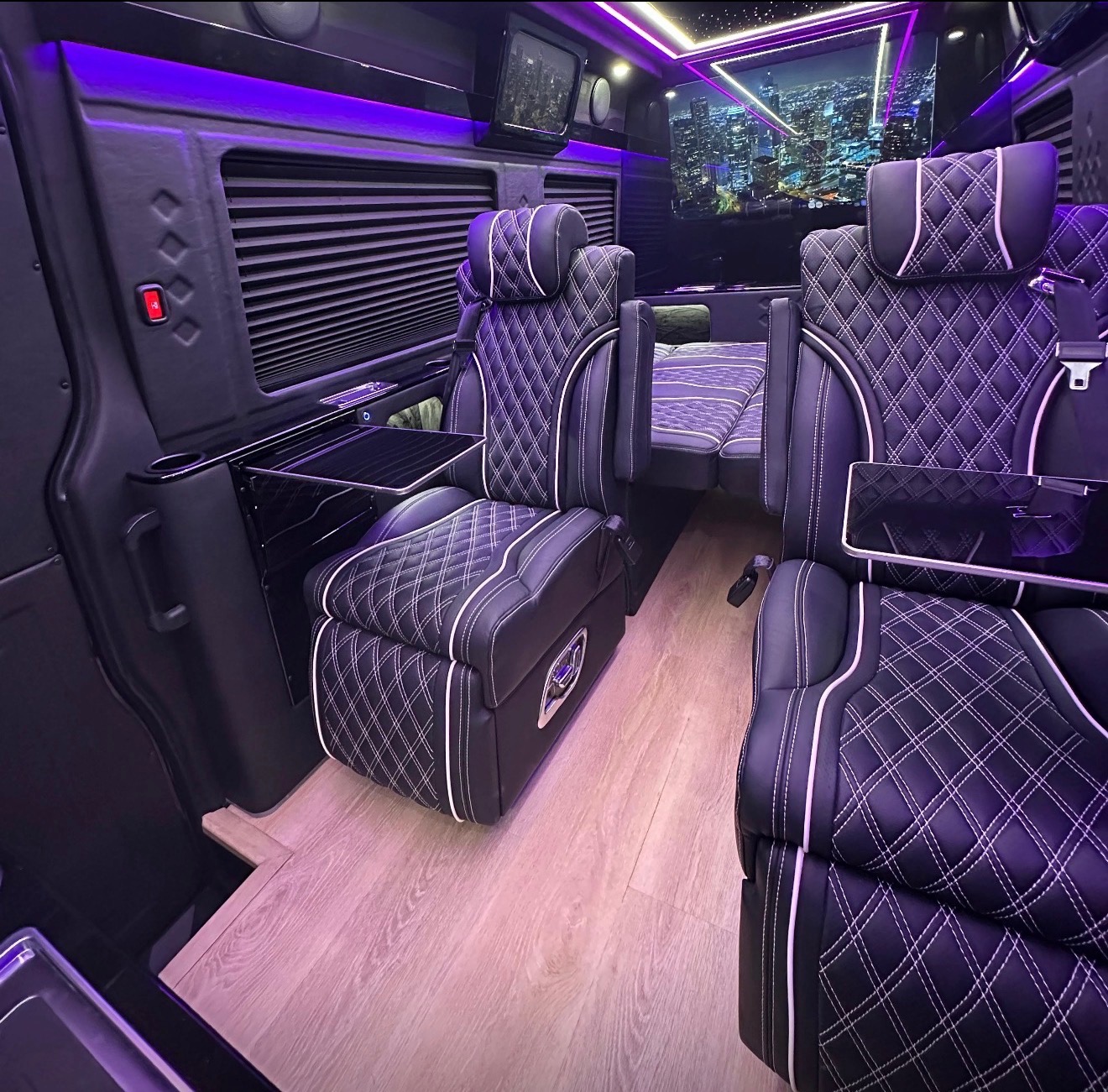 Black leather captain chairs with white diamond stitching in a lounge interior with wood-look floors