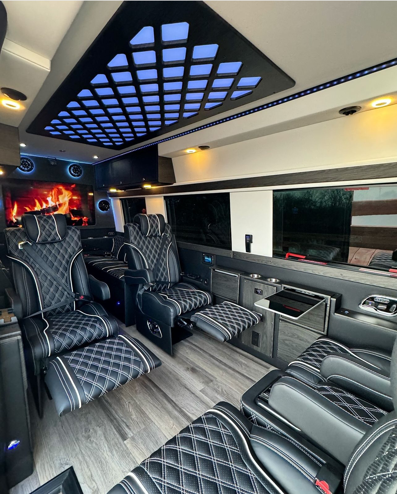 Reclining black leather captain chairs with white diamond stitching and a digital fireplace screen