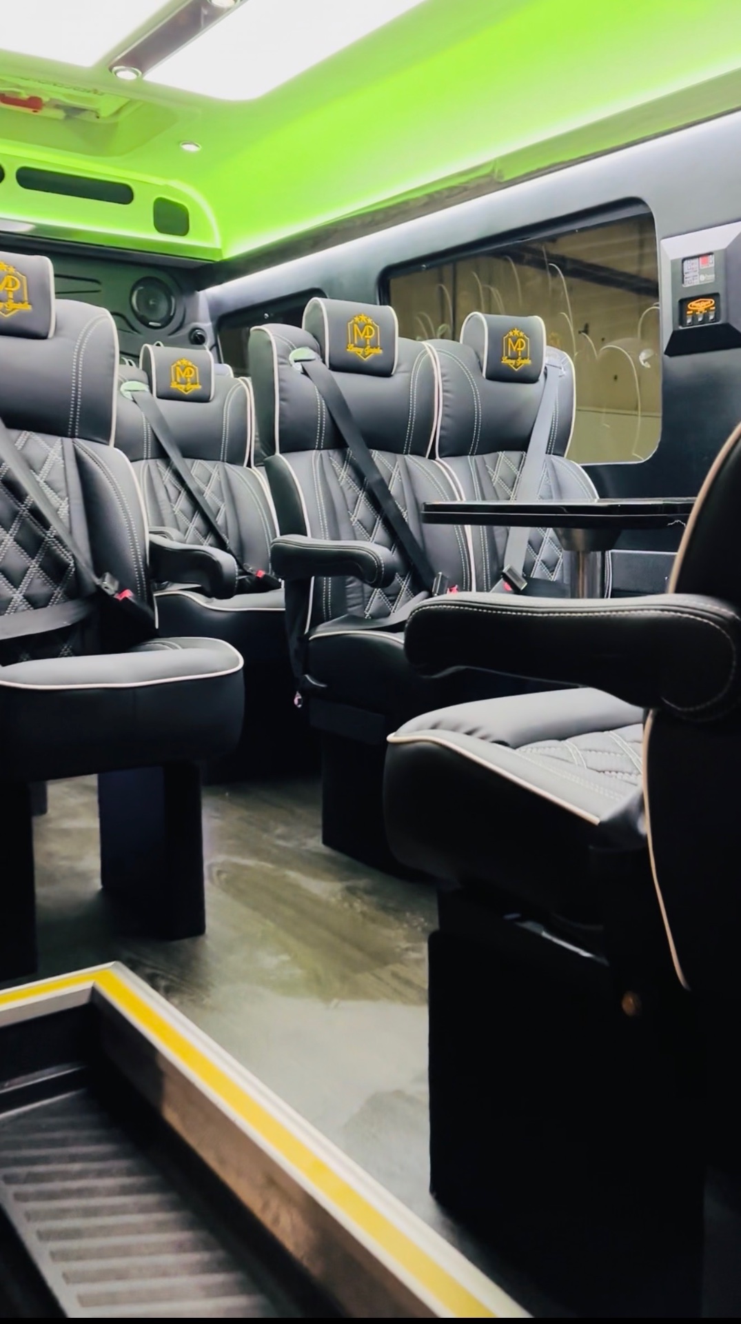Black leather captain chairs with white diamond stitching and gold crests under green ceiling lighting